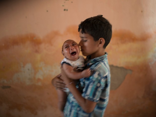 Foto de 23 de dezembro mostra menino Elison, de 10 anos, cuidando de seu irmão de 2 meses José Wesley, que nasceu com microcefalia, em Poço Fundo, no Pernambuco (Foto: AP Photo/Felipe Dana) no G1